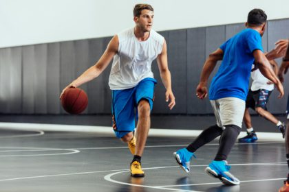 Male basketball player running with ball in basketball game