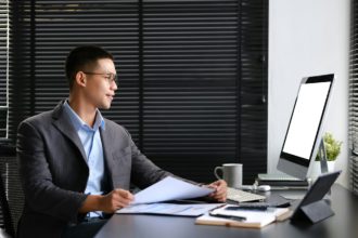 Successful businessman in suit looking at computer screen and working with financial reports.